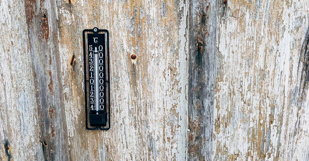 Un termómetro vintage montado en una pared de madera rústica. Perfecto para temas de nostalgia y monitoreo del clima.