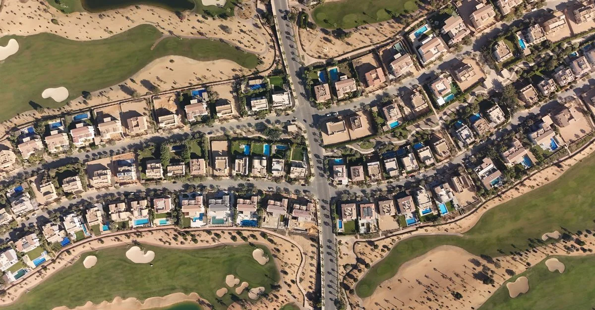 Vista aérea de las lujosas villas y el campo de golf en Sheikh Zayed, El Cairo, que muestra la arquitectura moderna y la exuberante vegetación.