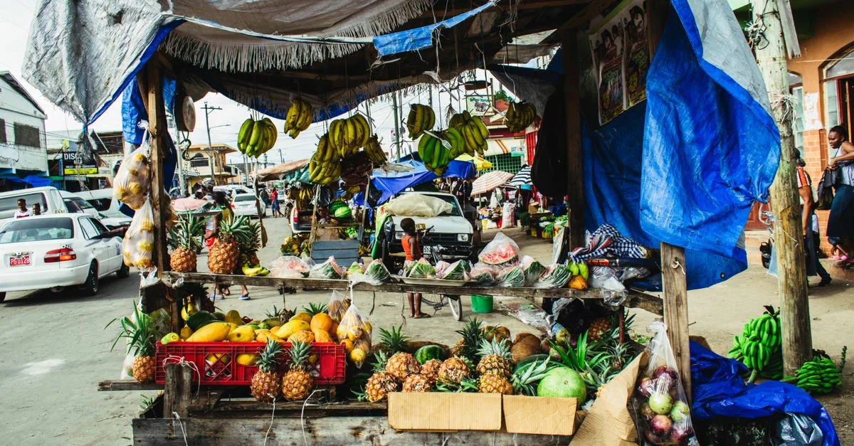 Frutas frescas exhibidas en un colorido puesto de mercado al borde de la carretera en una calle concurrida.