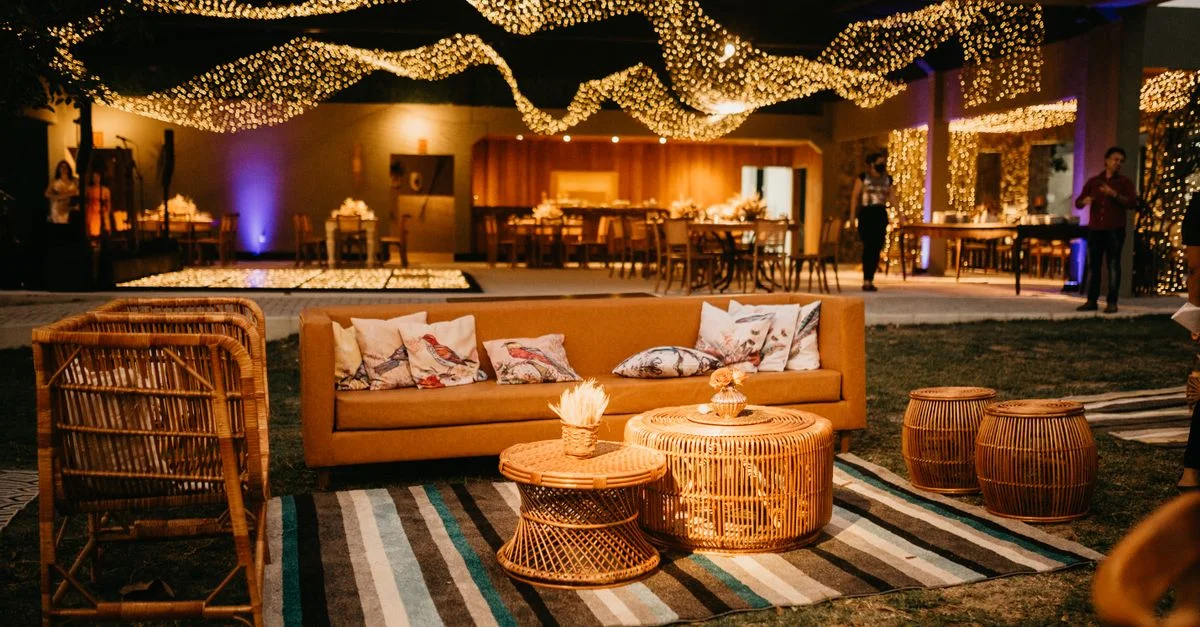 Espace extérieur chaleureux avec des meubles en osier et un éclairage d'ambiance pour un événement élégant en soirée.