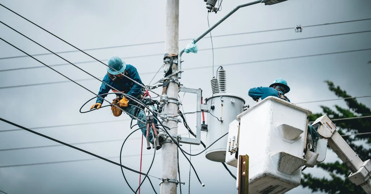 Electricistas en San José, Costa Rica, reparando líneas de alta tensión desde un elevador.