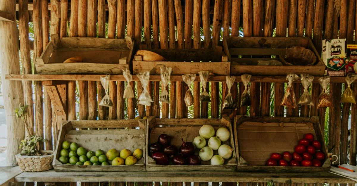 Puesto de mercado colorido que muestra frutas y verduras locales en cajas de madera.