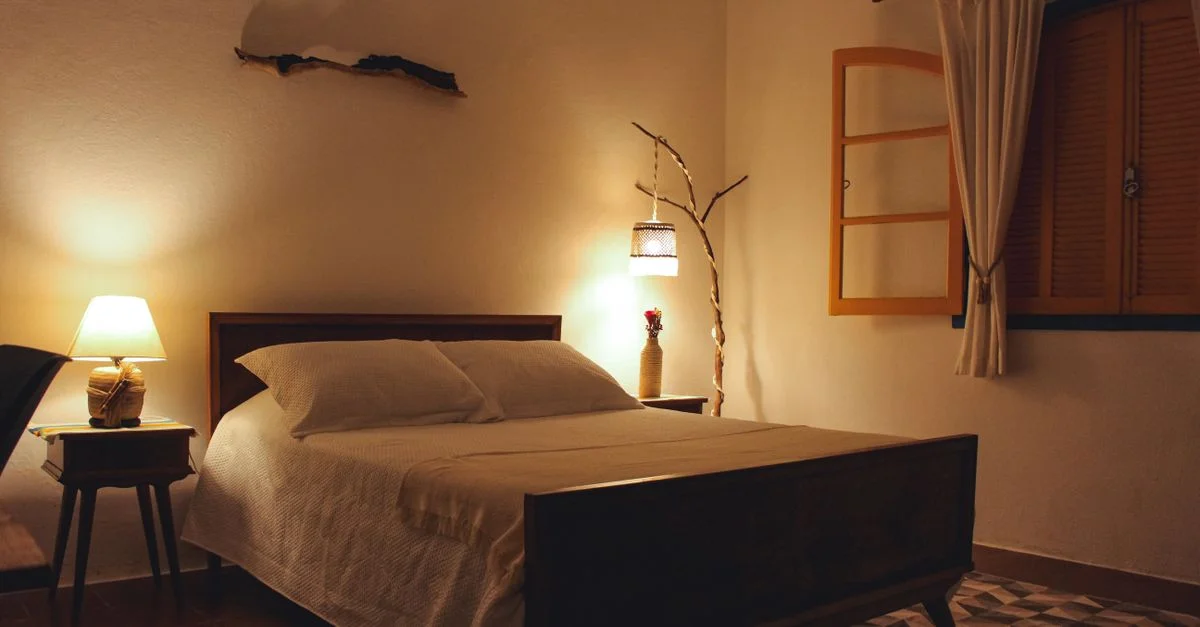 Un dormitorio sereno con iluminación cálida, cama de madera y detalles decorativos.