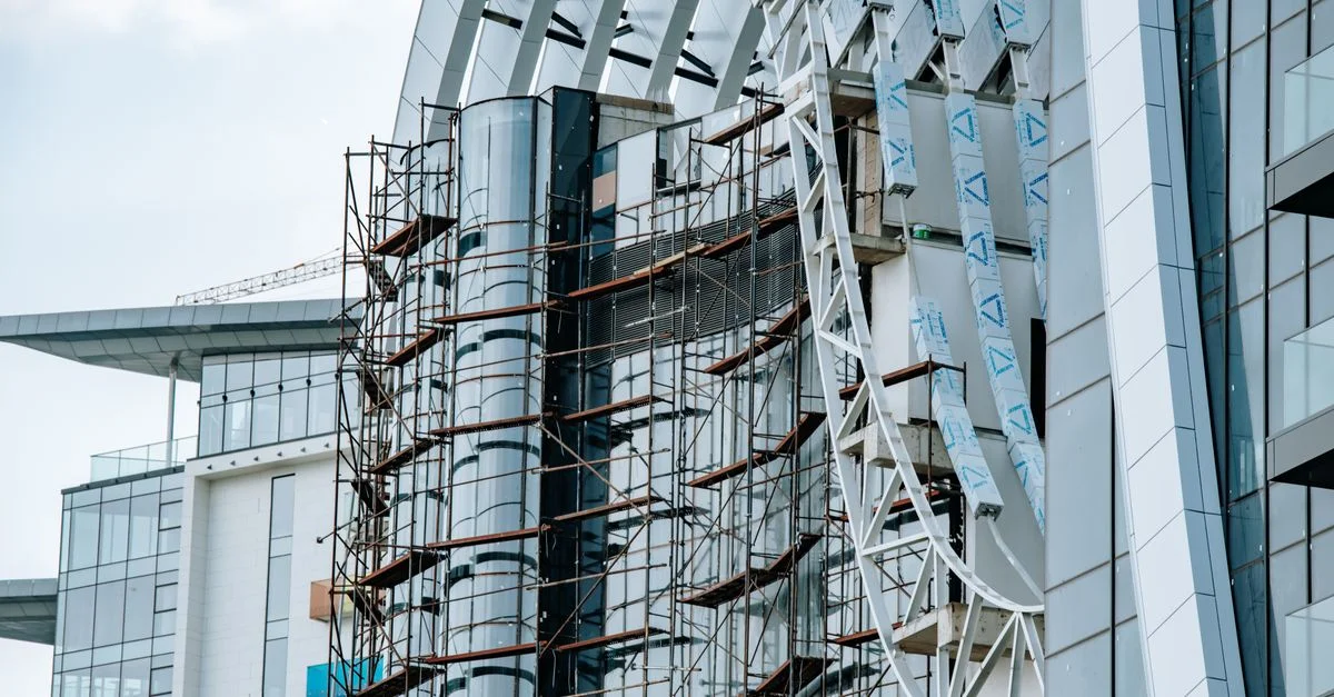 Un moderno edificio de gran altura en construcción, con andamiaje y paneles de vidrio.