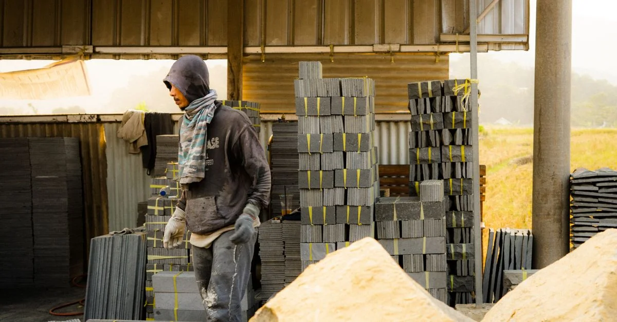 Un trabajador organiza losas de piedra en una planta de fabricación, lo que pone de relieve el trabajo industrial.