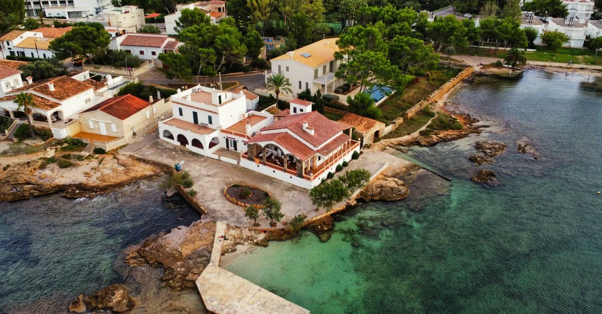 Toma aérea de casas encantadoras junto al mar y aguas turquesa en Mallorca, España.