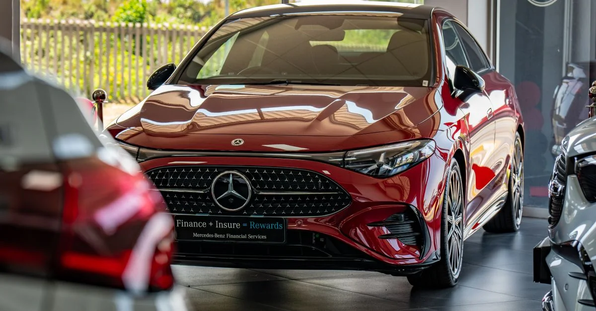 Un lujoso Mercedes-Benz rojo se exhibe en un lugar destacado de la sala de exposición de un concesionario de automóviles.