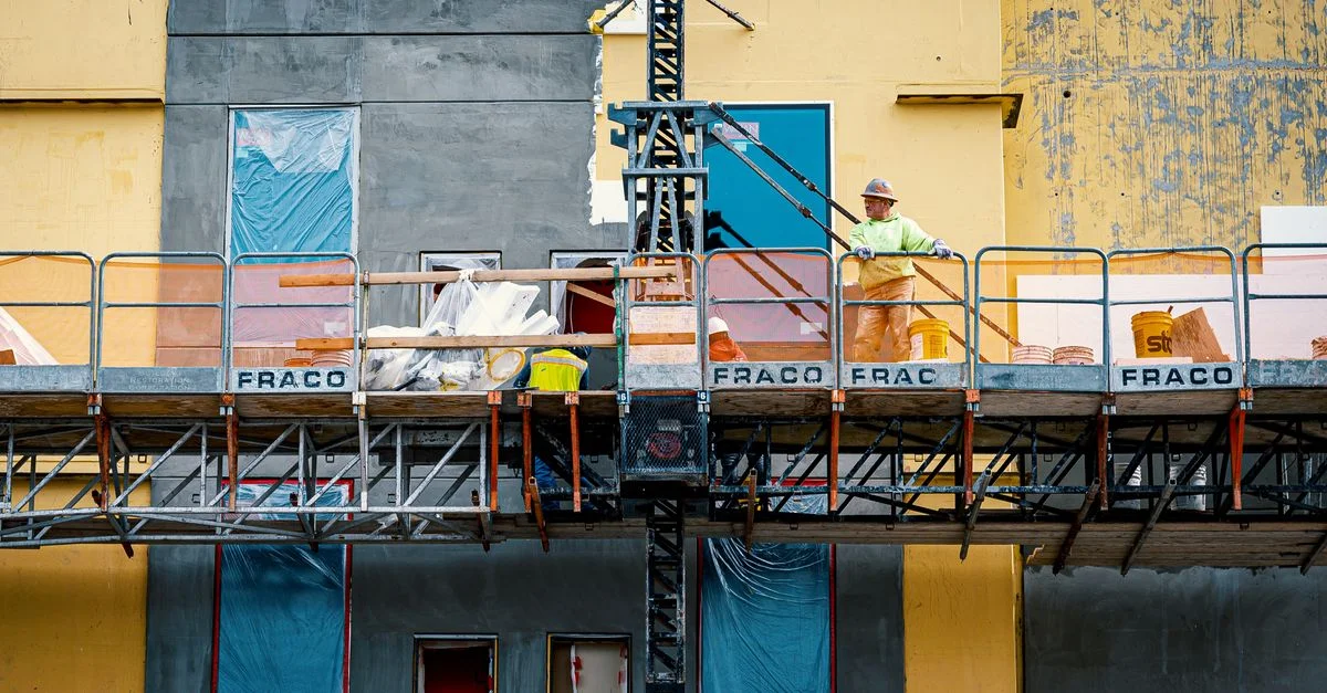 Trabajador de la construcción en andamios durante la renovación de la fachada del edificio.